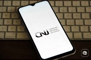 Smartphone exibindo o logo do CNJ em um teclado de computador